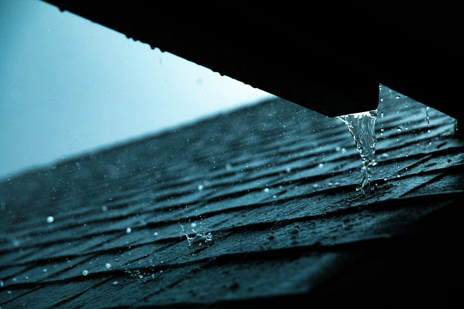 Rain runs off an asphalt shingle roof edge during a summer storm in Kansas